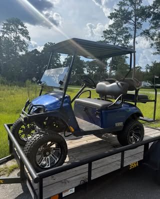 Blue lifted golf cart loaded on a trailer